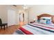 Bright bedroom with wood-look flooring, a bed with colorful bedding and a view into the en-suite bathroom at 5607 Tanagergrove Way, Lithia, FL 33547