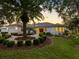 Elegant home exterior with lush landscaping, circular driveway, and decorative lighting at sunset at 5818 Cruiser Way, Tampa, FL 33615