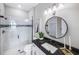 Modern bathroom with glass-enclosed shower, black fixtures, and a round mirror at 5949 Bluestar Ct, Lakewood Ranch, FL 34211