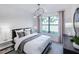 Bright bedroom featuring a large window with palm tree views, elegant lighting, and neutral decor at 5949 Bluestar Ct, Lakewood Ranch, FL 34211