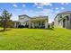 Large backyard showcases covered patios, ample green space, and mature trees for privacy at 612 Ozona Village Dr, Palm Harbor, FL 34683