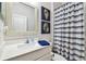 Bright bathroom featuring a white vanity, blue seashell art, and a blue and white striped shower curtain at 612 Ozona Village Dr, Palm Harbor, FL 34683