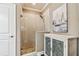 Beautifully tiled glass shower is adjacent to a cabinet with sailboat art for a stylish bathroom at 612 Ozona Village Dr, Palm Harbor, FL 34683