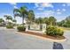 Ozona Village entrance featuring lush landscaping, mature palms and decorative community signage at 612 Ozona Village Dr, Palm Harbor, FL 34683