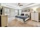 Spacious primary bedroom with a tray ceiling, ceiling fan, and shuttered windows provides a luxurious retreat at 612 Ozona Village Dr, Palm Harbor, FL 34683