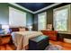 Dark toned bedroom with hardwood floors, dresser, lamps, and windows offering natural light, creating a cozy ambiance at 6341 Discovery Ln, Land O Lakes, FL 34638