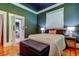 Well-lit bedroom with dark green walls, hardwood floors, two windows, a bench, and glimpses of the living space beyond at 6341 Discovery Ln, Land O Lakes, FL 34638