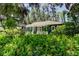 Exterior view of a blue home surrounded by lush green ferns and mature trees at 6341 Discovery Ln, Land O Lakes, FL 34638