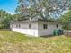The house has a big backyard with a tree and green trash and recycling bins at 6901 N 19Th St, Tampa, FL 33610