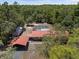 An aerial view of home with a red metal roof, a screened-in pool, and is nestled among Florida's lush green trees at 7095 South St, Webster, FL 33597