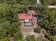 Aerial view of home featuring a screened-in pool with surrounding lush green trees and a red metal roof at 7095 South St, Webster, FL 33597