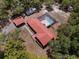 Aerial view of red roof house featuring a pool and several outdoor buildings amongst lush Florida trees at 7095 South St, Webster, FL 33597