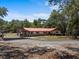 Exterior view of home with red roof, long driveway, and screened-in porch at 7095 South St, Webster, FL 33597