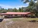 Charming single-story home with a red roof and brick accents, nestled among mature trees at 7095 South St, Webster, FL 33597