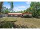 Charming home with a red roof and manicured lawn surrounded by trees at 7095 South St, Webster, FL 33597