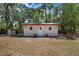 Exterior of a white outbuilding with a red roof, nestled in a tree-filled yard at 7095 South St, Webster, FL 33597