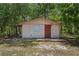 Exterior of a cozy outbuilding with neutral paint, red door and small covered entry at 7095 South St, Webster, FL 33597