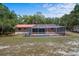 Back view of home showcasing an enclosed pool deck featuring a screened-in pool and a low-pitched red metal roof at 7095 South St, Webster, FL 33597