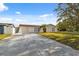 Inviting single-story home featuring a long driveway and a well-maintained lawn with a small palm tree at 7325 Calder Dr, New Port Richey, FL 34653