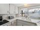 Bright kitchen featuring white cabinets, stainless steel appliances, and a window overlooking the backyard at 7325 Calder Dr, New Port Richey, FL 34653