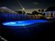 Backyard swimming pool with blue lighting at night, surrounded by a wooden fence, creating an inviting atmosphere at 8520 Woodall Ct, Tampa, FL 33615