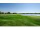 Expansive golf course view with players, lush green fairways, and a serene lake in the background at 8926 Garner Ct, Trinity, FL 34655