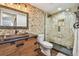 Renovated bathroom featuring a unique stone wall, a vessel sink, and a glass-enclosed shower with a rainfall showerhead at 9425 Blind Pass Rd # 802, St Pete Beach, FL 33706