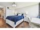 Bright bedroom features hardwood floors, a white-framed bed with navy bedding, a modern ceiling fan, and a small work space at 9425 Blind Pass Rd # 802, St Pete Beach, FL 33706