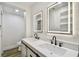 Modern bathroom with double vanity, illuminated mirrors, contemporary faucets, and wood-look flooring at 10011 N Annette Ave, Tampa, FL 33612