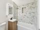 Bathroom features a modern vanity, a bathtub, and a shower with marble-patterned tile surround and built-in niche at 10011 N Annette Ave, Tampa, FL 33612