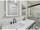 Bathroom with double vanity, illuminated mirrors, modern faucets and updated shower with marble tile at 10011 N Annette Ave, Tampa, FL 33612