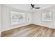 Bright bedroom with wood-look floors, ceiling fan, and two windows providing natural light at 10011 N Annette Ave, Tampa, FL 33612
