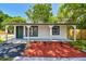 Exterior showcasing fresh paint, new landscaping, and the inviting green front door of this charming home at 10011 N Annette Ave, Tampa, FL 33612