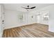 Open-concept living room with modern ceiling fan, wood flooring, and access to the adjacent kitchen area at 10011 N Annette Ave, Tampa, FL 33612