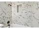 Close-up of a shower with marble-patterned tile surround, and black shower head and controls at 10011 N Annette Ave, Tampa, FL 33612