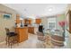 Open kitchen and dining area featuring wood cabinets, breakfast bar seating, and a glass-top dining table at 10502 Atlee St, New Port Richey, FL 34654