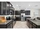 Modern kitchen featuring dark cabinetry, stainless steel appliances, granite countertops and an island with barstool seating at 11760 Winterset Cove Dr, Riverview, FL 33579