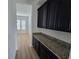 Butler pantry featuring sleek dark cabinets, granite countertops, and convenient access to dining area at 11839 Cross Vine Dr, Riverview, FL 33579