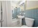 A vintage bathroom with blue tile, tub/shower, pedestal sink and decorative mirror at 1211 E Park Cir, Tampa, FL 33604