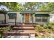 Charming home featuring a cozy front porch with awning, a vibrant yellow door, and manicured landscaping at 1211 E Park Cir, Tampa, FL 33604