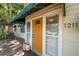 A bright yellow front door of a cozy home entrance, framed by windows and complemented by a dark wood porch at 1211 E Park Cir, Tampa, FL 33604