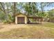Storage shed and carport in grassy backyard, surrounded by mature trees at 12514 Avery Rd, Thonotosassa, FL 33592