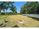 Spacious backyard with a fire pit, mature trees, and a white fence at 135 Rodney Ct, Palm Harbor, FL 34684