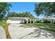 Single-story home with a front-facing two car garage, arched doorway, and manicured lawn at 135 Rodney Ct, Palm Harbor, FL 34684