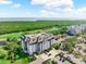 Beautiful aerial view of multi-story building with golf course, pond, lush trees, and blue skies at 14820 Rue De Bayonne # 208, Clearwater, FL 33762