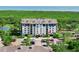 Elevated view of the condo building with a well-manicured landscape, ample parking, and an adjacent scenic pond at 14820 Rue De Bayonne # 208, Clearwater, FL 33762