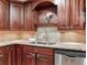 Close up of stainless steel kitchen sink and appliances, complemented by custom cabinets and granite countertops at 14820 Rue De Bayonne # 208, Clearwater, FL 33762