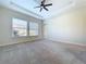 Large bedroom with a tray ceiling, fan, neutral carpet, and plenty of natural light from the big windows at 1723 Whitewillow Dr, Wesley Chapel, FL 33543