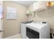 Well-lit laundry room with modern washer and dryer units and storage shelving at 19487 Roseate Dr, Lutz, FL 33558