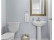 Cozy half bathroom featuring a pedestal sink, toilet, decorative mirror, and wicker basket at 212 N Bradford Ave, Tampa, FL 33609